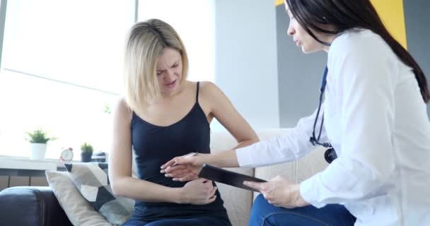 Infelice giovane paziente femminile con dolore addominale parlando medico di casa primo piano — Video Stock