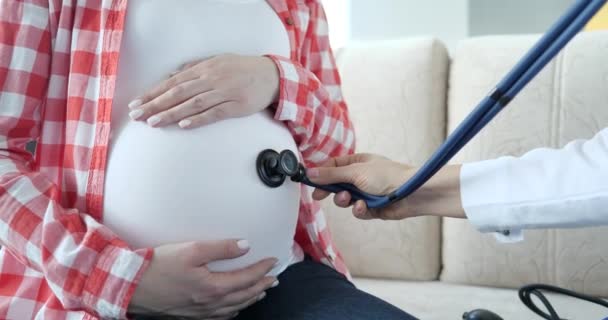 Медсестра осматривает живот беременной женщины в закрытом помещении — стоковое видео