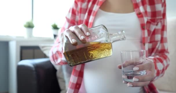 Mujer embarazada vierte alcohol en primer plano de vidrio — Vídeo de stock