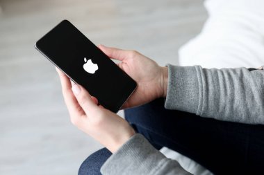 Kadın elinde ekran logosu olan yeni bir iPhone tutuyor. İllüstrasyon Editörü