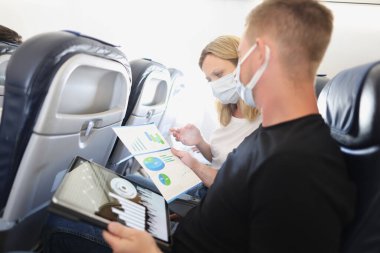 Koruyucu maskeli ve uçakta belgeleri olan insanlar.