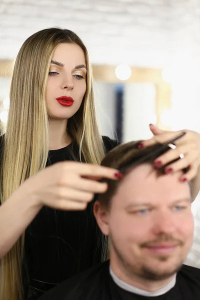 Stylish woman hairdresser combing hair to a man — Stock Photo, Image