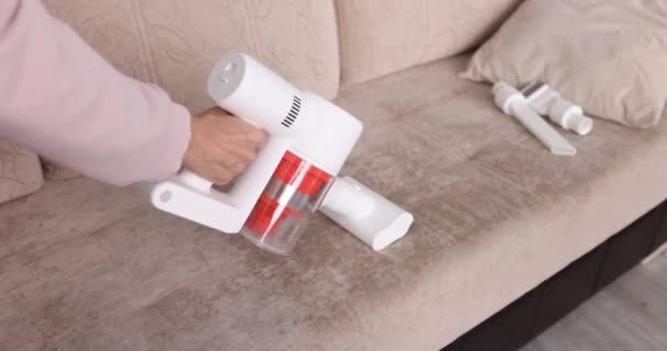 Dona de casa limpeza sofá em casa com aspirador de pó sem fio close-up filme 4k — Vídeo de Stock