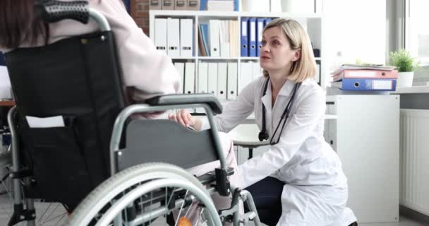 Médico neurólogo revisando reflejos de rodilla con martillo de percusión a mujer discapacitada en silla de ruedas 4k película cámara lenta — Vídeos de Stock