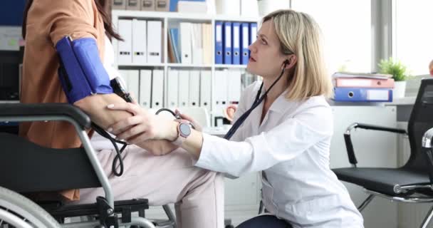 Woman doctor measuring blood pressure of pregnant disabled woman in wheelchair 4k movie — Stock Video