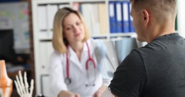 Doktor travmatolog kolunda alçıyla hastayla iletişim kuruyor ve X-ray 4K filmi yavaş çekim gösteriyor.