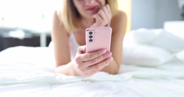 침대에 누워서 휴대 전화를 손에 들고 누워 있는 젊은 여자가 4k 영화를 클로즈업한다 — 비디오