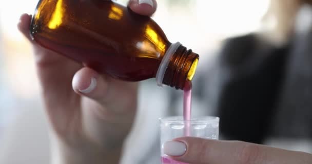 Pessoa derrama xarope de tosse do frasco para o copo de medição close-up — Vídeo de Stock