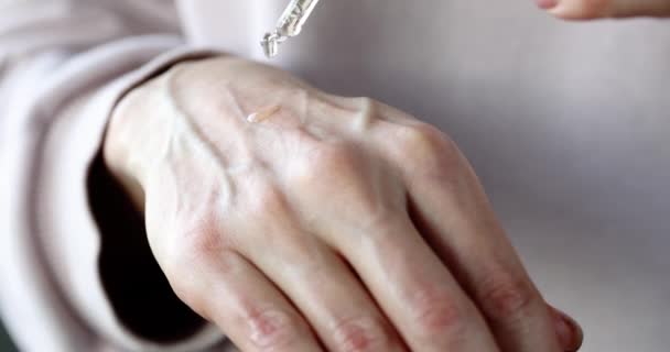 Vrouwelijke hand druppelt etherische olie op de huid van de hand voor hydraterende closeup — Stockvideo