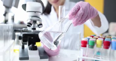 Laboratuvardaki bilim adamı şeffaf sıvı yakın çekimini inceliyor.