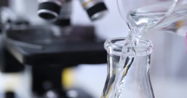 Scientifique en gant verse liquide clair dans fiole gros plan — Video