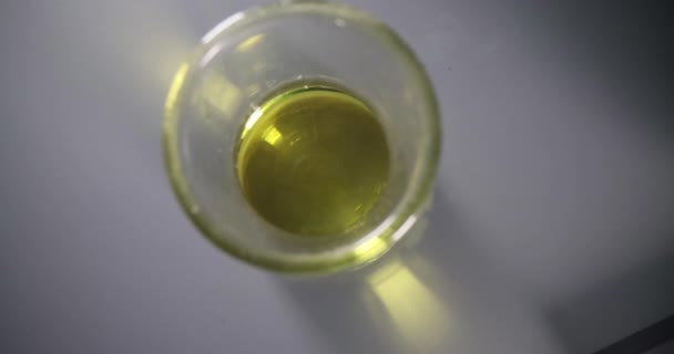 Óleo amarelo transparente no fechamento do tubo de ensaio químico de vidro — Vídeo de Stock