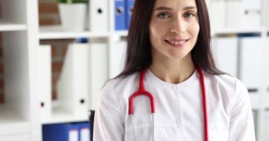 Beyaz önlüklü, steteskoplu gülümseyen kadın doktor portresi.