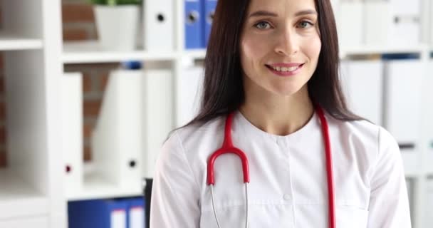 Портрет улыбающейся женщины-врача в белом халате со стетоскопом крупным планом — стоковое видео