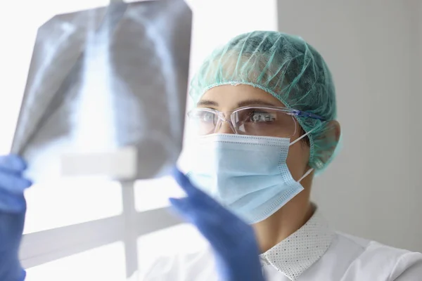 O doutor esperto examina o raio x dos pulmões do paciente, diagnóstico na clínica — Fotografia de Stock