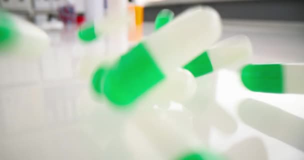 Un sacco di capsule mediche verdi bianche che cadono sul tavolo primo piano film 4k slow motion — Video Stock