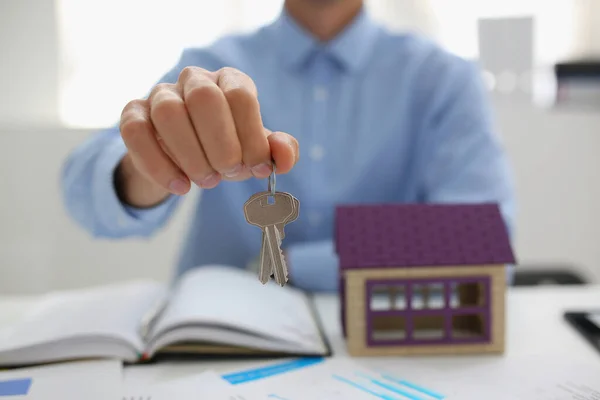 Hombre trabajador en traje dar la llave para desbloquear nueva casa en miniatura, comprar un nuevo alojamiento — Foto de Stock