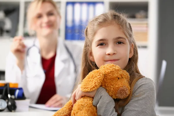 Carino bambino sorridente al pediatra, bambino abbraccio orsacchiotto giocattolo preferito — Foto Stock