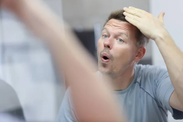 Homem de meia idade tocar seu novo penteado, olhar em espelho de reflexão — Fotografia de Stock