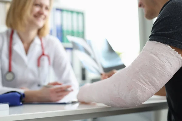 Paciente do sexo masculino com bandagem no braço sentado na consulta traumatologista close-up — Fotografia de Stock