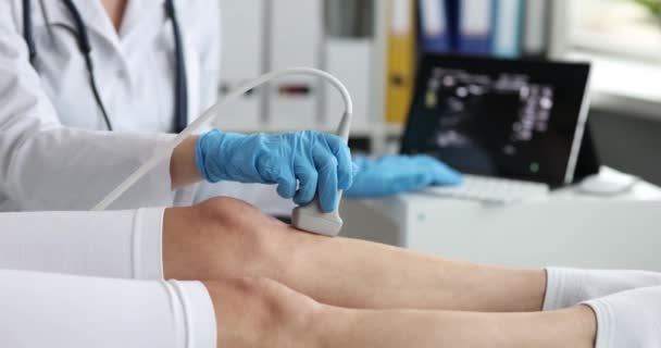 Врач в резиновых перчатках сканирует ногу пациента с помощью ультразвукового аппарата — стоковое видео