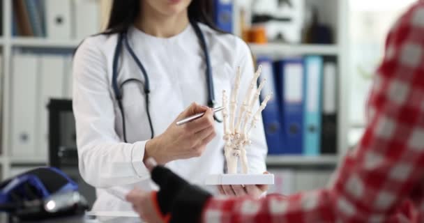医師は、手を閉じてモデルに患者の骨損傷を示しています — ストック動画