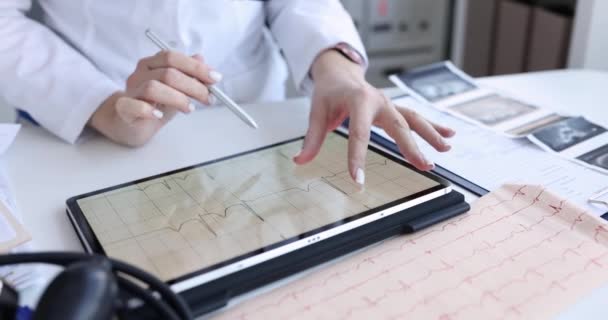 Кардиолог изучает электрокардиограмму пациента на планшетах крупным планом — стоковое видео
