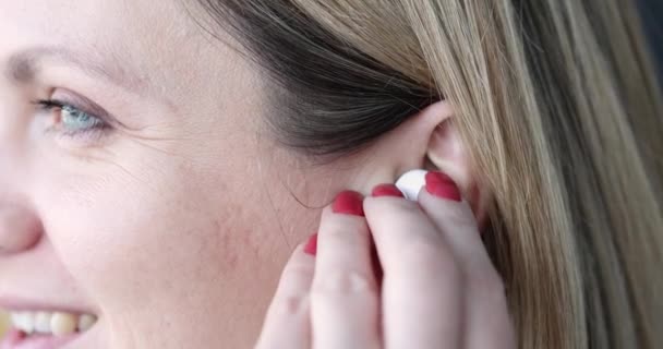 Mulher bonita jovem insere fones de ouvido sem fio em close-up ouvido — Vídeo de Stock