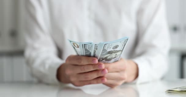 Empresario sosteniendo billetes de cien dólares en las manos en el primer lugar de trabajo — Vídeos de Stock