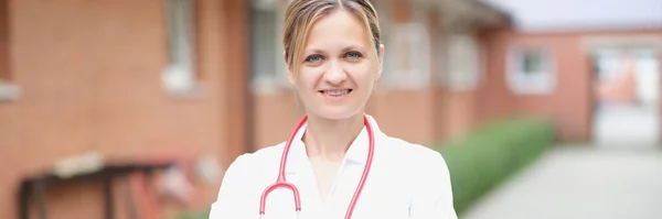 Портрет улыбающейся женщины-врача со сложенными руками на улице — стоковое фото