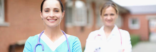 Dua dokter wanita tersenyum berdiri dengan tangan terlipat — Stok Foto