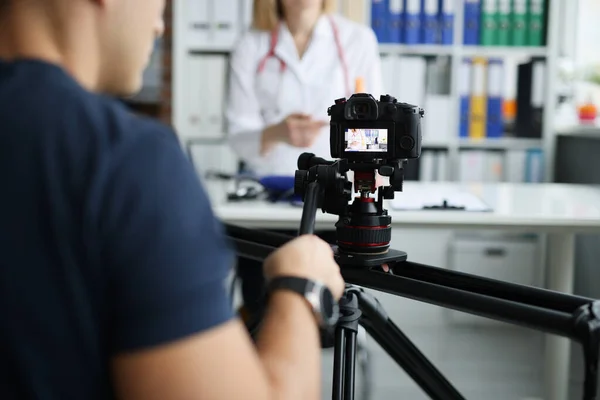 Photographe filmant médecin à la caméra à l'aide de trépied et curseur gros plan — Photo