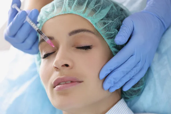 Jonge dame krijgt injectie van botox in haar neus, cosmetoloog met behulp van spuit — Stockfoto