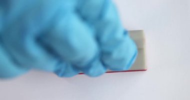 Plastik eldivenli doktor kırmızı omikron damgalı 4K yakın çekim filmi koyuyor.