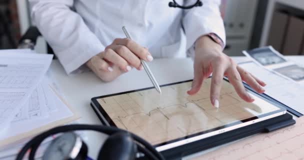 Врач-кардиолог изучает кардиограмму на цифровом планшете крупным планом 4К фильма — стоковое видео