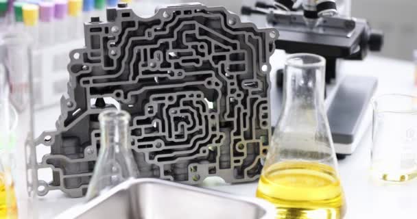 Automatisk transmission ventil krop liggende i kemisk laboratorium nær kolber med olie closeup 4k film – Stock-video