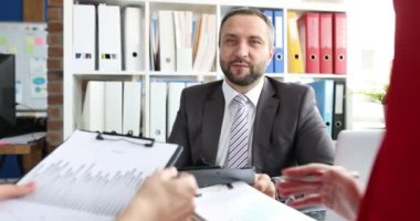 Bir grup iş ortağı 4k bürosundaki belgelerin grafiklerini tartışıyor.
