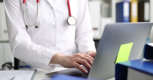 Doctor escribiendo en el teclado del ordenador portátil en la clínica de primer plano película 4k — Vídeo de stock