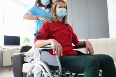 Doktor tekerlekli sandalyedeki bir kadına omuz masajı yapıyor.