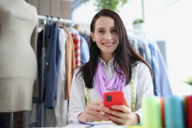 Kadın terzinin elinde akıllı telefon var, yakın plan.