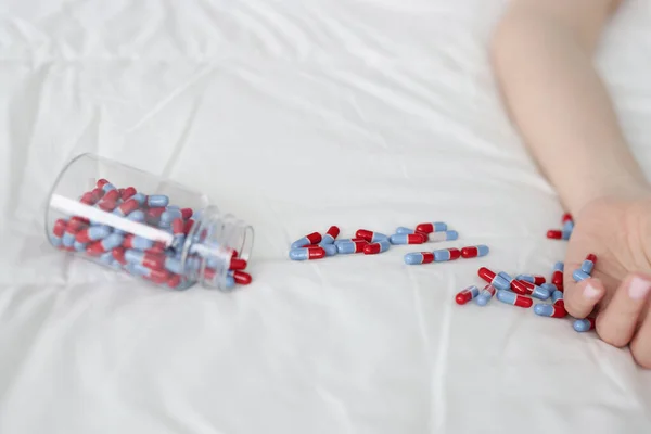 Blue red capsules are scattered on a white bed — Stock Photo, Image