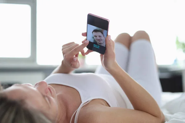 Жінка лежить на спині і дивиться в телефон — стокове фото