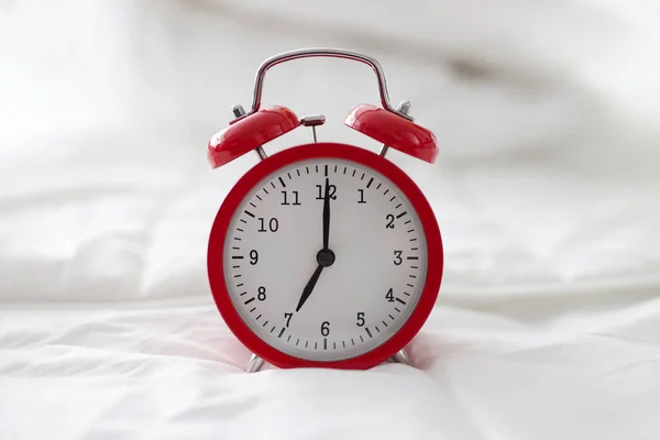 Reloj despertador rojo en una manta blanca, primer plano — Foto de Stock
