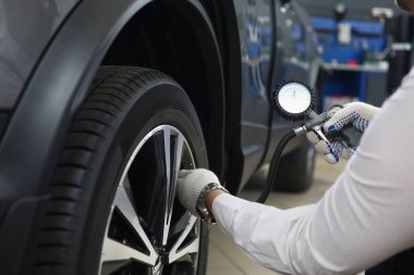 İş yerinde özel bir aletle lastikleri pompalayan otomekanik.