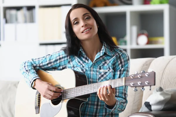 Mulher morena bonita tocando guitarra na sala de estar, mulher passar tempo livre para aprender novo hobby — Fotografia de Stock