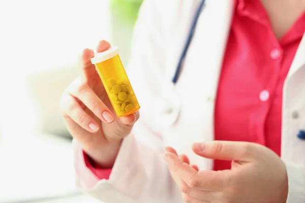 Orvos tartja műanyag tartály tele apró fehér tabletták, női gyakornok reklámozza gyógyszert — Stock Fotó