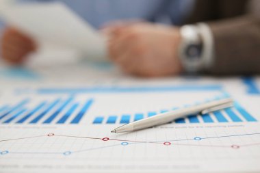 Gümüş bir kalem üzerinde bir diyagram, bulanık bir rapor yatar