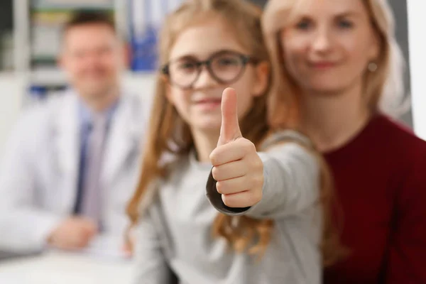 Mãe e filha na consulta no centro médico, médico sorrindo em segundo plano — Fotografia de Stock