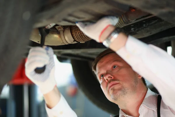 Automático con la pieza de reparación de la llave inglesa debajo del automóvil, manitas ocupadas en el trabajo — Foto de Stock