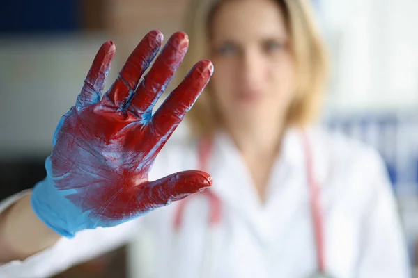Врач показывает стоп-жест с перчаткой на руке с кровью крупным планом — стоковое фото